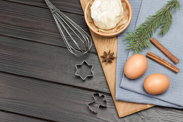 Eggs, cinnamon sticks and spruce twigs on gray napkin. Cookie cutter molds and whisk