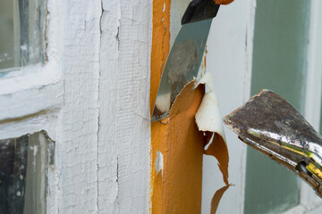 The process of cleaning the old entrance wooden door from paint. Worker's hands in orange gloves...