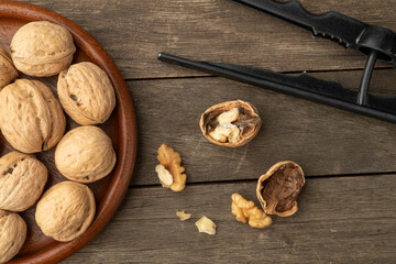 Walnuts, nut cracker and cracked nuts over wooden table