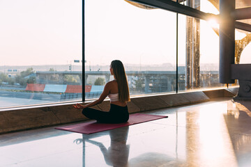 Anonymous woman meditating near airport window
