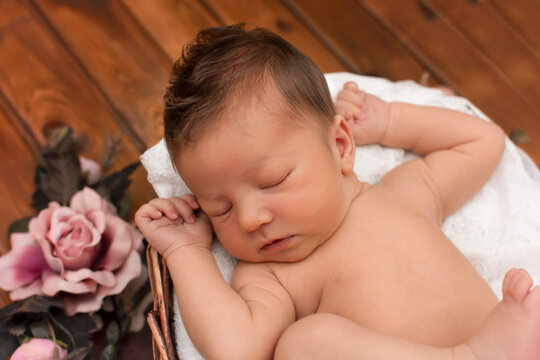 Sweet boy sleeps in a basket with a white blanket. Sleeping cute newborn baby. First days of life. One week old baby in wrap lying. Studio photos