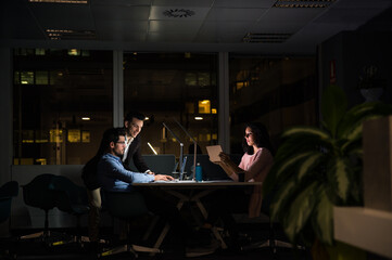 Cheerful young group of colleagues working late in office