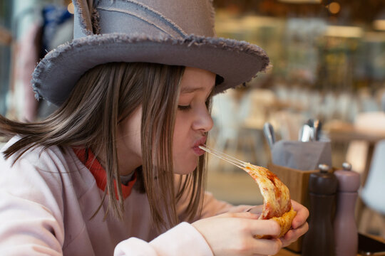 Teen girl eat pizza in a funny hat