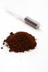 Syringe filled with coffee powder, coffee powder pile beside