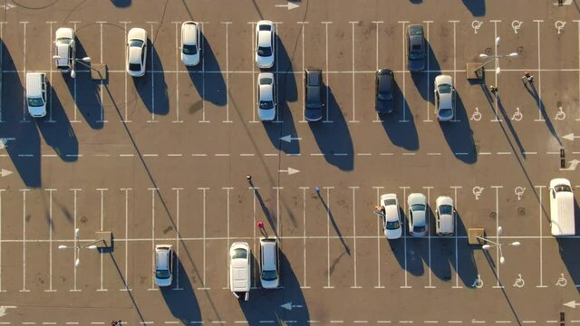 Aerial top view from drone places for disabled people on parking lot of the business center, shopping mall (supermarket) with cars and empty parking spots at day. Transport. City. Urban. 4k footage