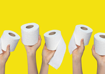 Hands holding toilet paper rolls on yellow background
