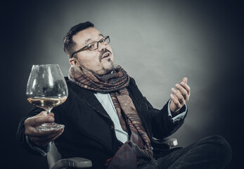 Solid cheerful man in kerchief sitting with glass of wine