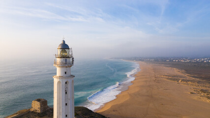 Drone views of the Trafalgar Lighthouse on the Costa de la Luz in Caños de Meca, Cadiz Andalucia, Spain. Faro de Trafalgar from above on a beautiful day with clouds and the blue sea. © Avril