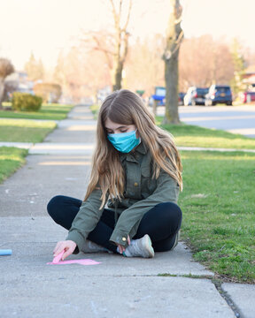 Child Drawing Heart Outside with Chalk with Mask