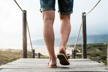 Man walking along boardwalk against misty ocean coast