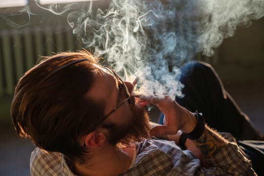 A bearded man smokes a cigarette