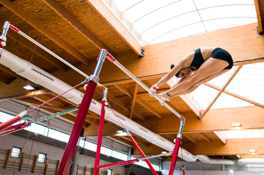 young artistic gymnast woman performing and training uneven bars