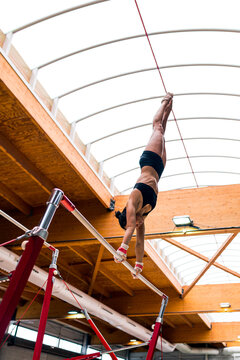 young artistic gymnast woman performing and training uneven bars