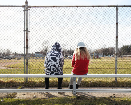 Two Tweens Sitting at Empty Park bench Outside Alone
