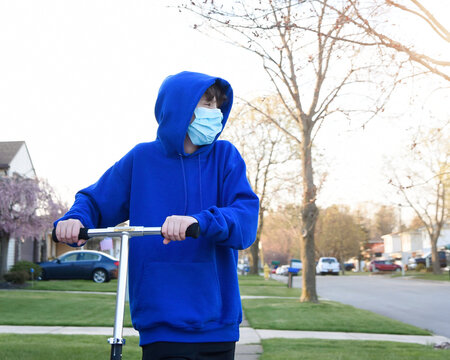 Boy Wearing a PPE Mask Outside with Scooter