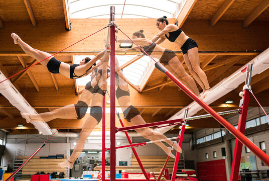 young artistic gymnast woman performing and training uneven bars