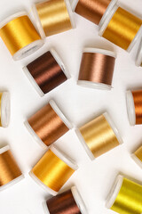 Bright colourful flat lay with lots of spoools for sewing with metal yellow and golden threads, flat lay