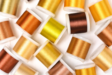 Bright colourful flat lay with lots of spoools for sewing with metal yellow and golden threads, flat lay