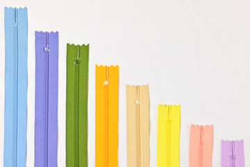 Texture of colourful zippers together for sewing, flat lay against white background, empty space