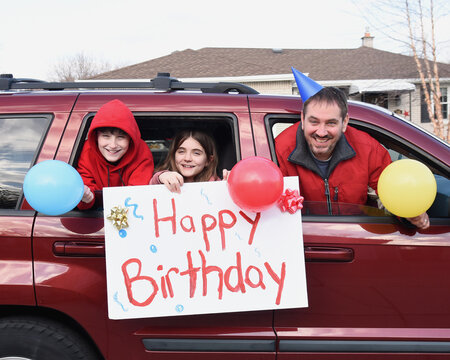 Family Driving By House With Happy Birthday Sign