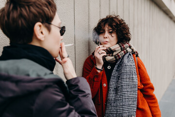 Young woman smoking cigarettes together her girlfriend.