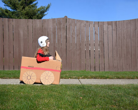 Child Sitting in Cardboard Car Outside