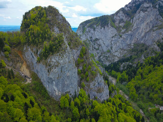 Aerial drone view over a steep cliff and a tunnel through a rocky mountain peak. Cheia Gorges, Capatanii Massif, Carpathia, Romania.
