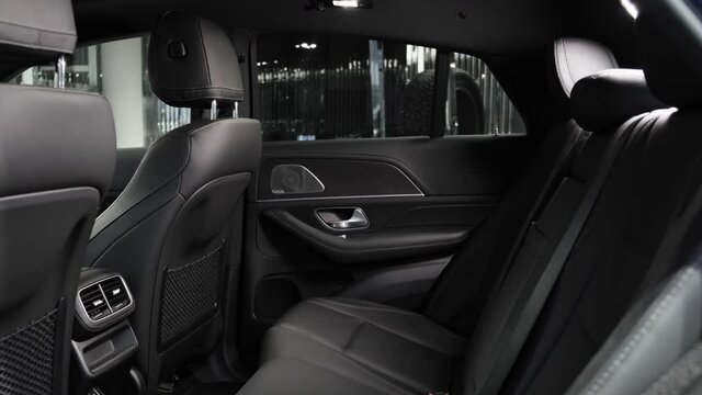 Rear seats of passengers of the new premium SUV. Black leather interior with comfortable seats of the new car.