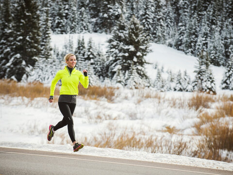 Caucasian woman running on snowy road