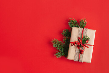 Craft gift box with spruce branch on a red background. Holiday eco-friendly concept.