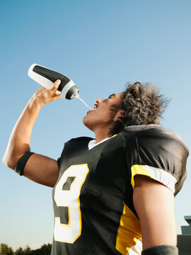 Hispanic football player drinking water