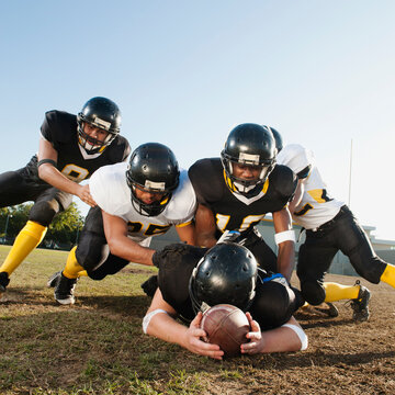 Football players tackling player on football field