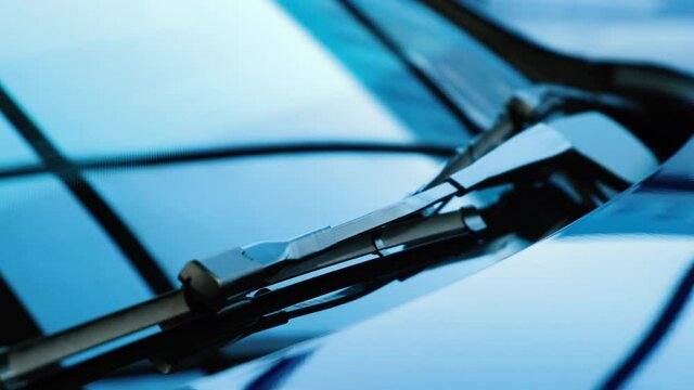 Close-up of a car wiper on the windshield of a new car. Abstract reflections on car glass