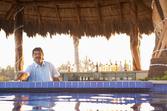 Hispanic bartender working near poolside