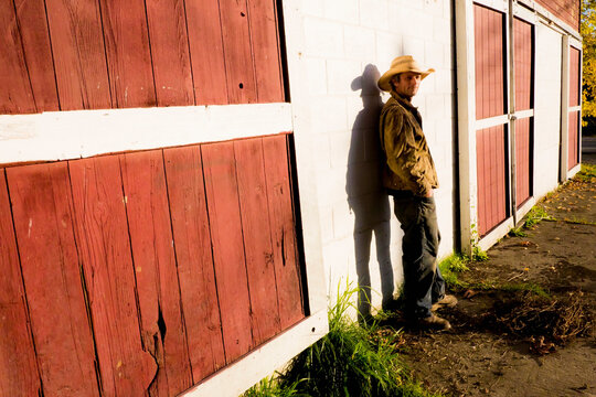 Caucasian farmer leaning on barn wall