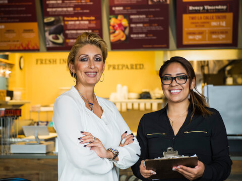 Hispanic business owner and employee smiling in cafe