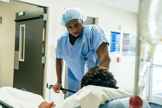 Black nurse talking to boy in hospital bed
