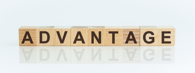 Wooden blocks with the text: advantage. The text is written in black letters and is reflected in the mirror surface of the table.