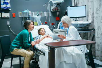 Caucasian doctor with digital tablet talking to mother and daughter in hospital