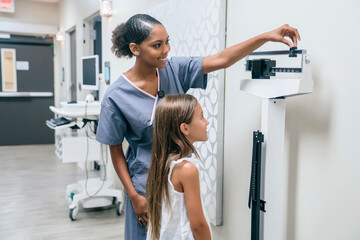 Nurse weighing girl on scale