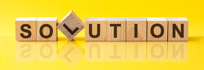 solution word is made of wooden building blocks lying on the yellow table, concept