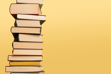 Pile of books stacked on a yellow background with space for copy