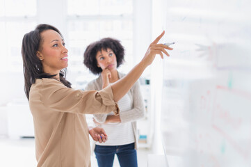 African American businesswomen at whiteboard in office