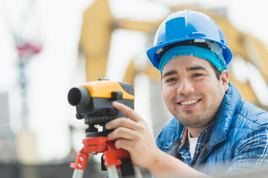 Mixed race engineer using theodolite at construction site