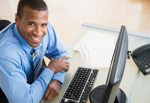Portrait of smiling Hispanic businessman at computer