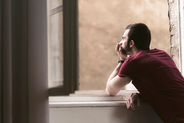 Portrait of a young man looking through the window