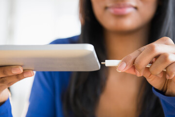 Mixed race woman plugging in digital tablet
