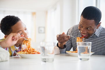Father and son eating together at table