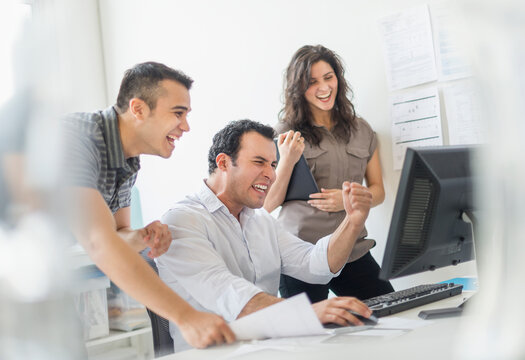 Hispanic business people cheering together in office