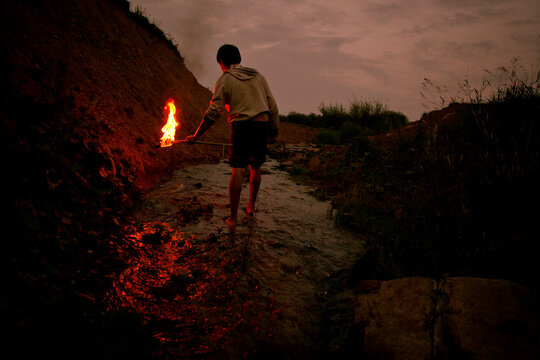 Mari man holding torch in rural creek